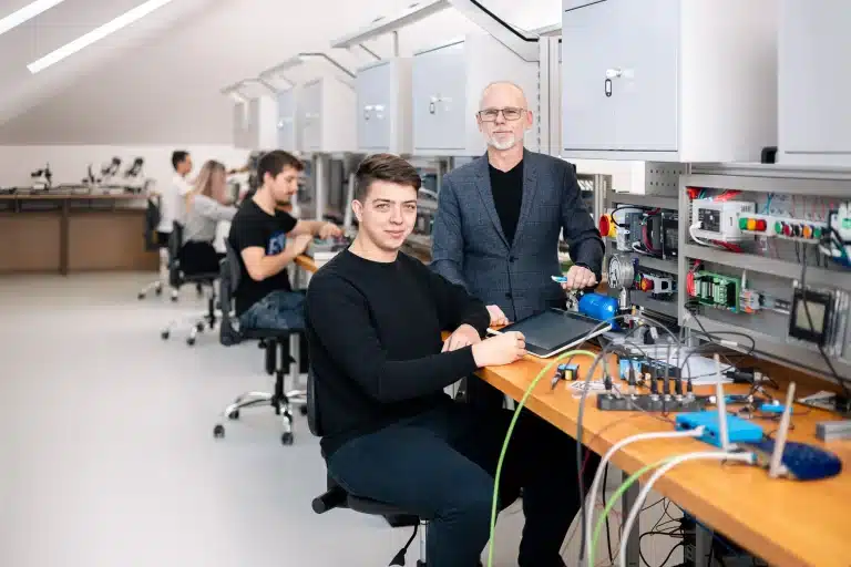 Dwóch mężczyzn w pracowni automatyki i elektroniki z panelem sterowania