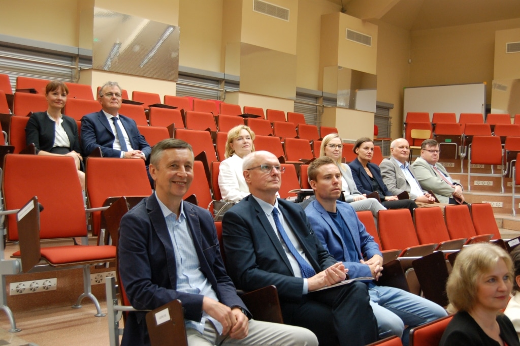 Uczestnicy konferencji naukowej „Aktywność podmiotów gospodarczych” siedzą w sali.