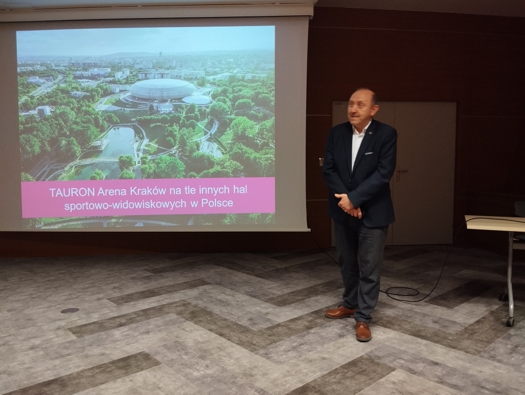 Mężczyzna prezentuje TAURON Arena Kraków na tle innych hal sportowych w Polsce.