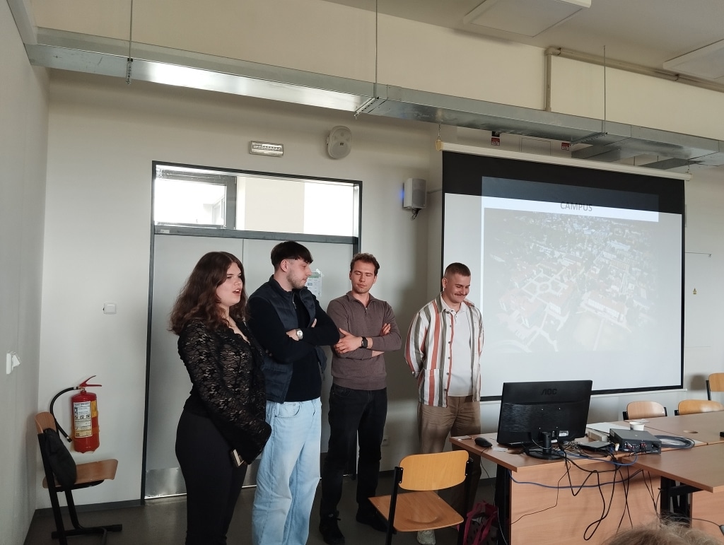 Studenci zarządzania VŠTE prezentują projekt na tle mapy kampusu.