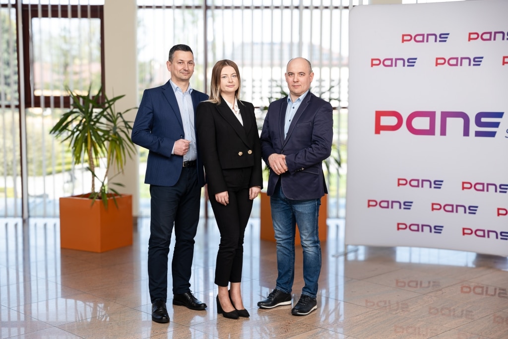 Zespół PANS: trzej profesjonaliści stoją przed logo firmy
