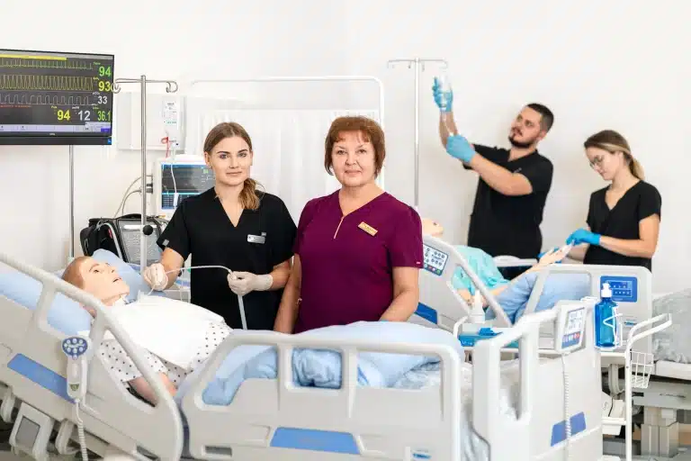 Pielęgniarki ćwiczą na fantomie w sali szpitalnej, monitor EKG.