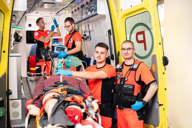 Ratownicy medyczni ćwiczą resuscytację na manekinie w karetce.