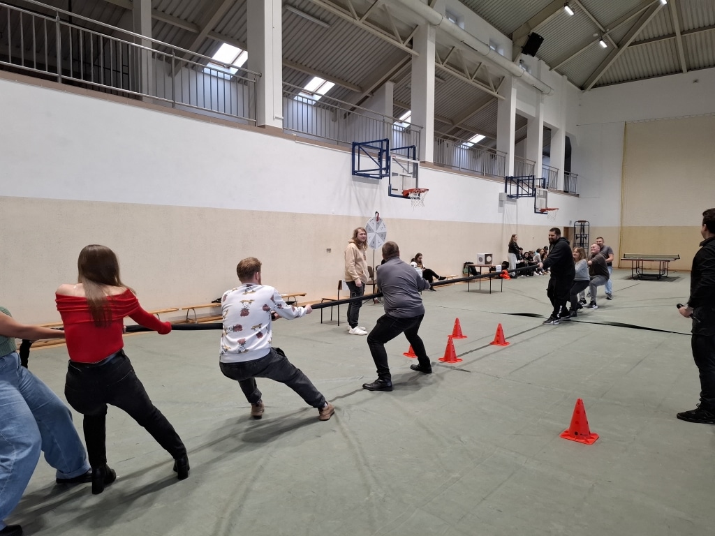 Studenci rywalizują w przeciąganiu liny podczas Dnia Studenta w hali sportowej.