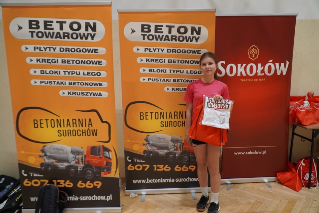Dziewczyna z nagrodami na tle banerów BETON TOWAROWY i SOKOŁÓW