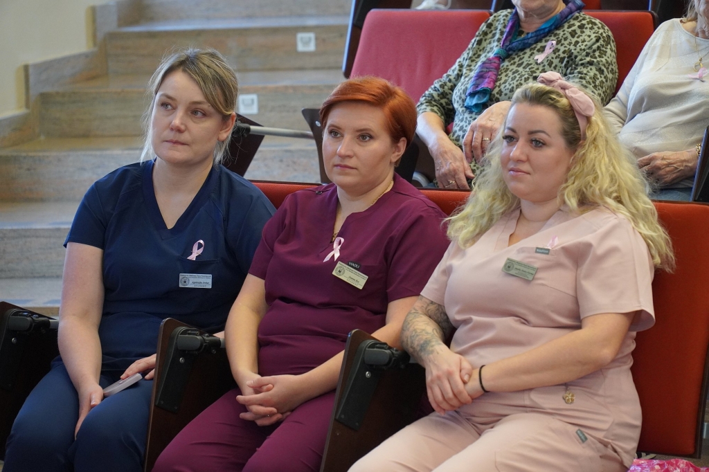 Trzy kobiety w strojach medycznych na sympozjum Różowego Października.