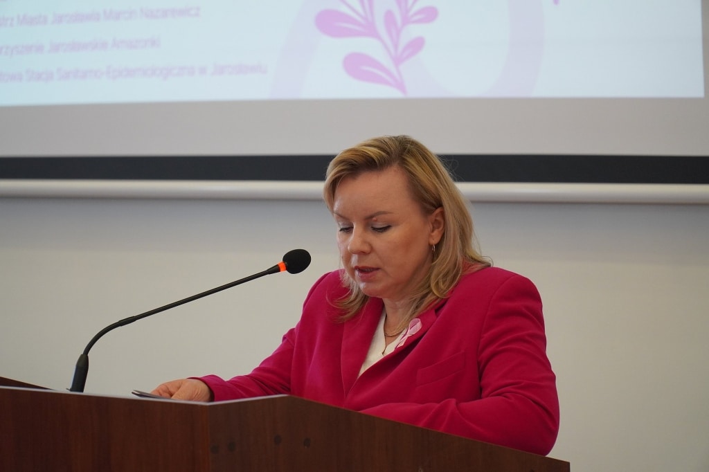 Kobieta w różowej marynarce przemawia na sympozjum naukowo-szkoleniowym w Różowym Październiku.