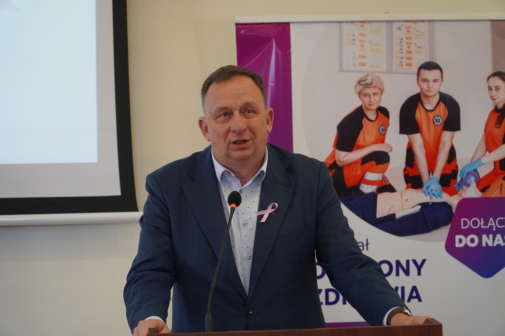 Mężczyzna w garniturze przemawia na sympozjum Różowy Październik.