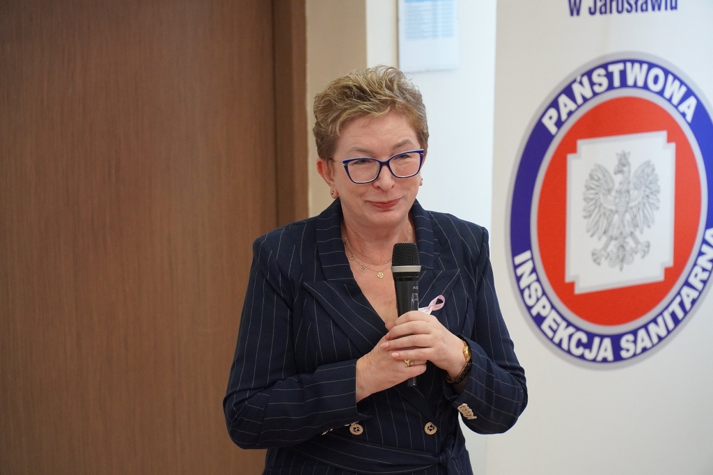Kobieta w okularach i różowej wstążce podczas sympozjum Różowy Październik