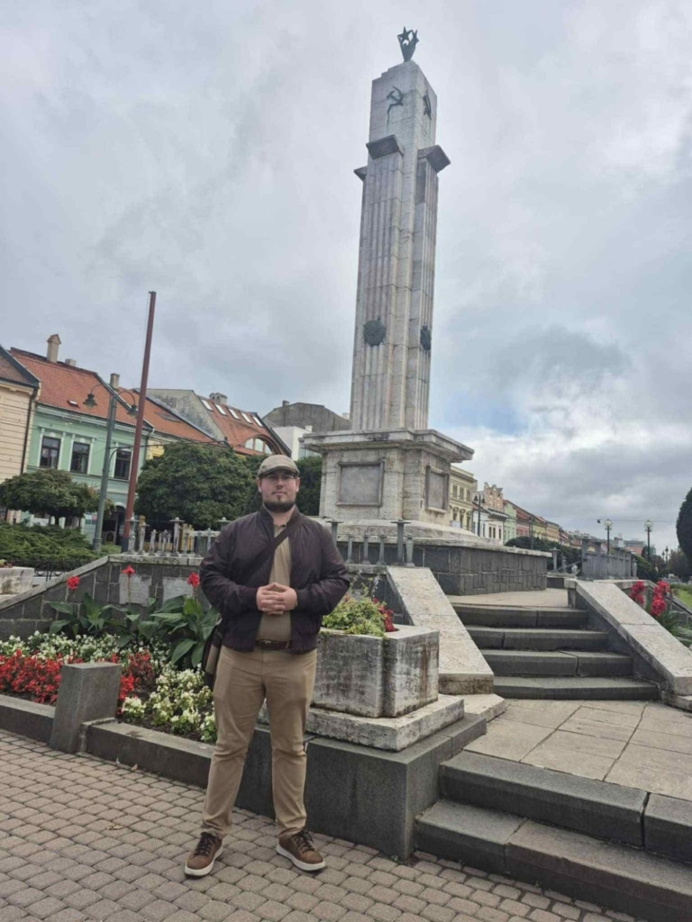 Mężczyzna na tle pomnika w centrum Preszowa podczas wizyty studyjnej