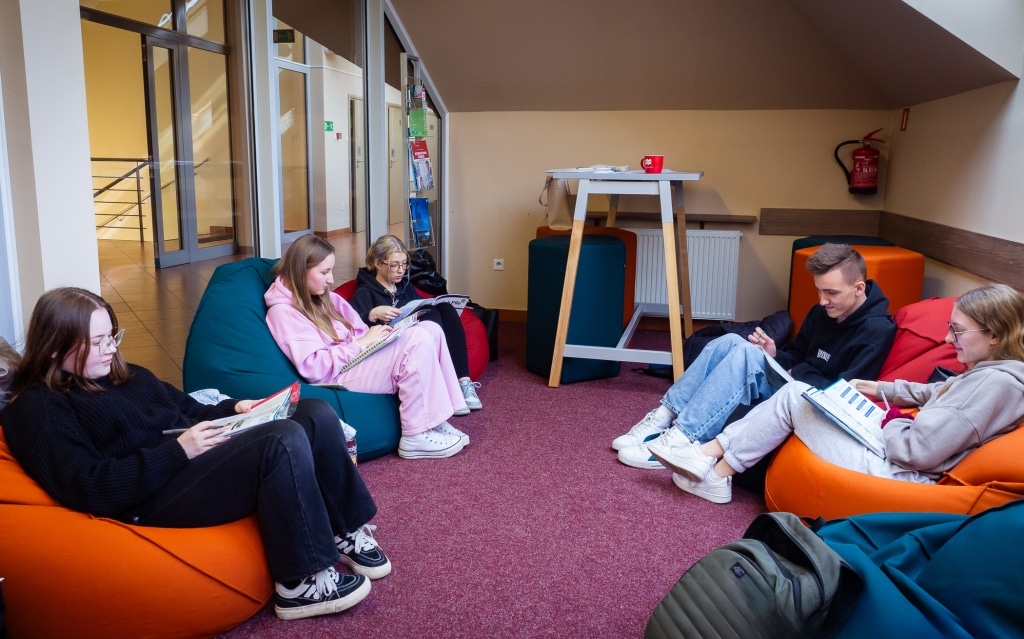 Studenci w nowej przestrzeni relaksu i nauki, siedzący na pufach i uczący się