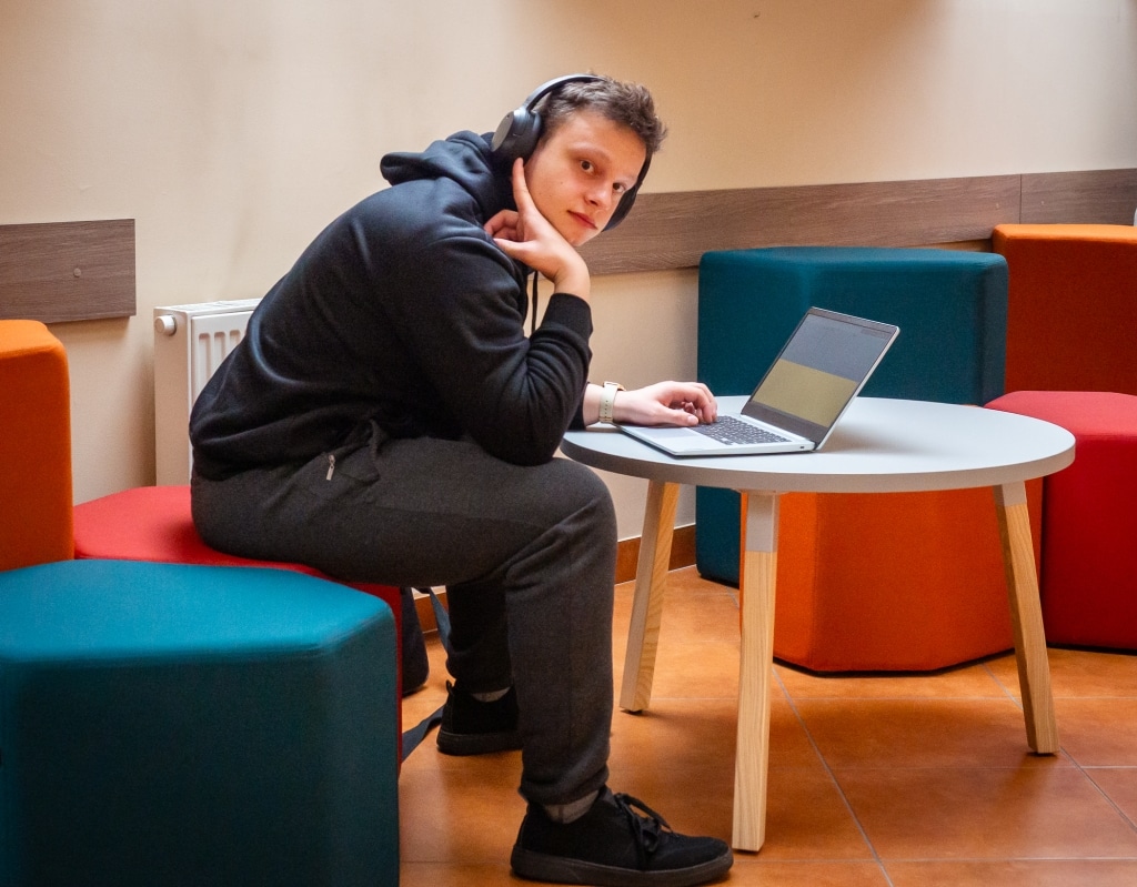 Student w słuchawkach korzysta z laptopa w nowej przestrzeni relaksu.
