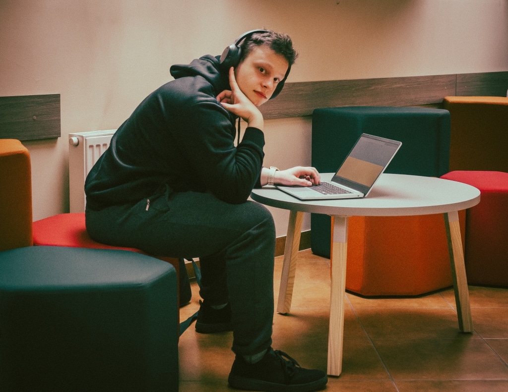 Student w słuchawkach pracuje na laptopie w nowej przestrzeni relaksu.