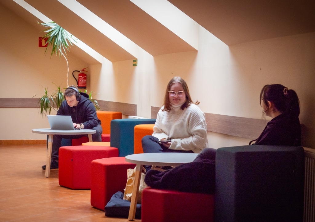 Studenci w nowej przestrzeni relaksu i nauki przy stołach i kolorowych pufach