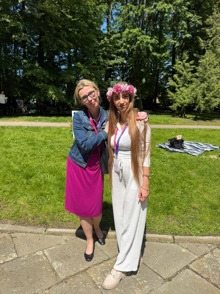 Dwie kobiety na pikniku rodzinnym, jedna w wianku z kwiatów.