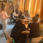 Studentka psychologii prowadzi warsztaty dla młodzieży w sali lekcyjnej.