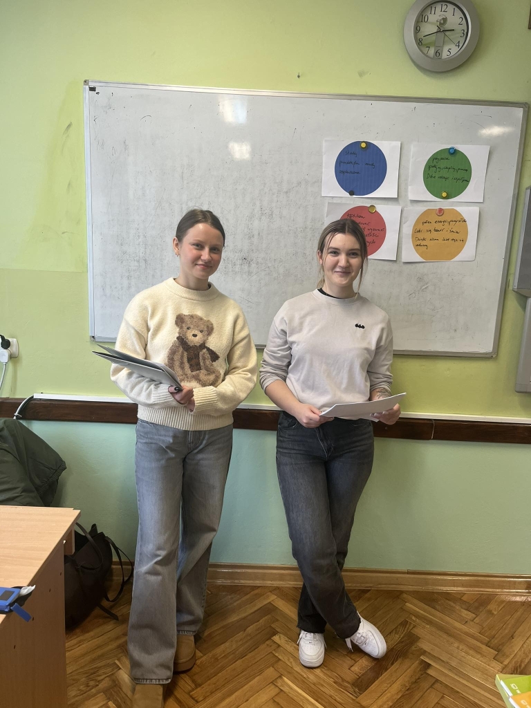 Studentki psychologii na tle tablicy w szkole podstawowej