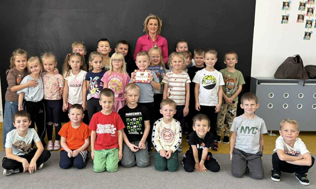 Dorośli czytają dzieciom: grupa dzieci i dorosła kobieta w klasie.