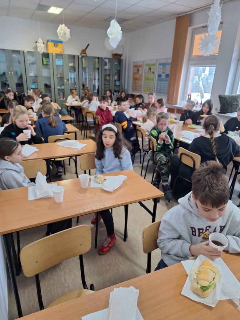 Dzieci jedzą drugie śniadanie w klasie podczas spotkania Przyrodniczego Uniwersytetu Dzieci.