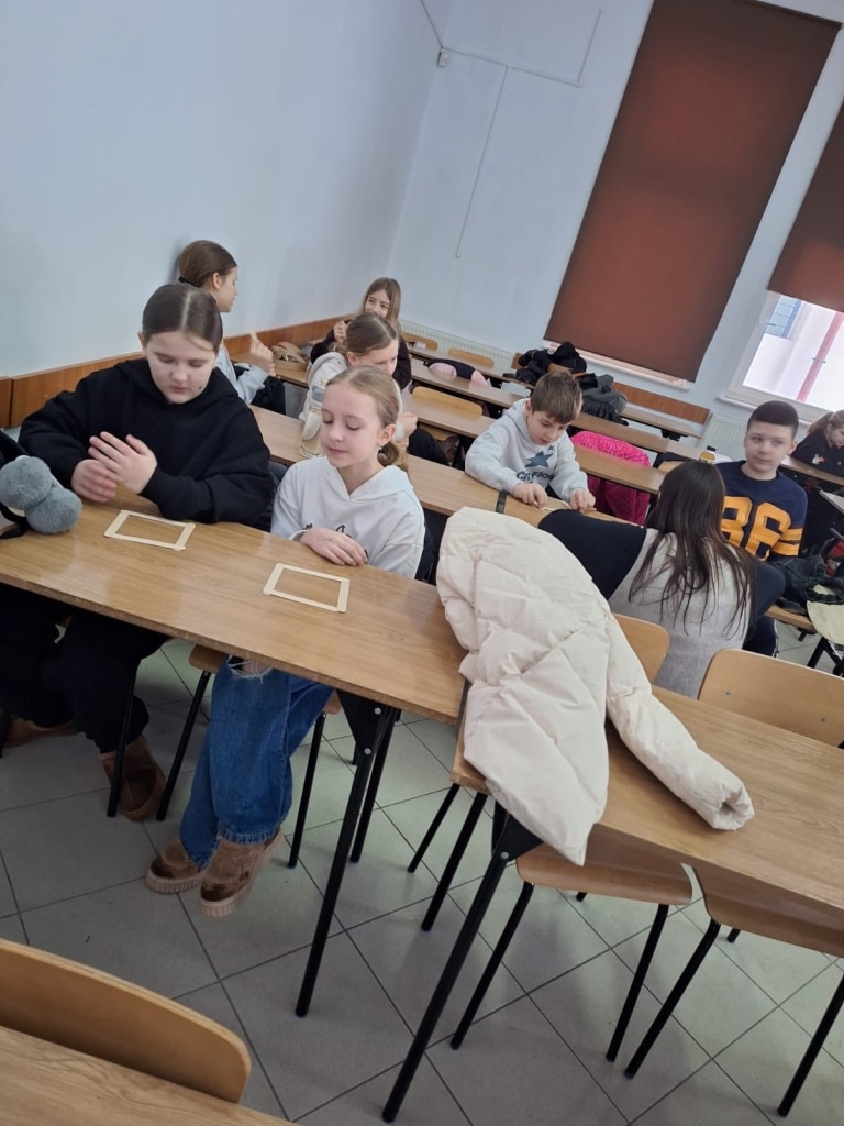 Dzieci na zajęciach przyrodniczych, pracujące przy ławkach.