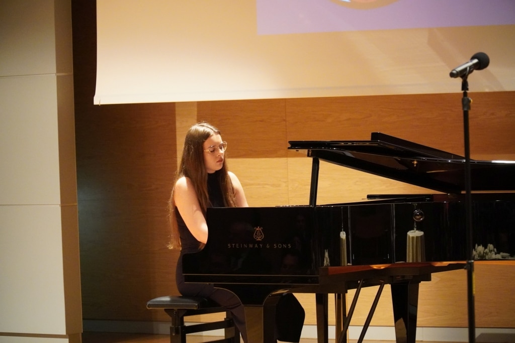 Młoda kobieta gra na fortepianie Steinway & Sons podczas występu.