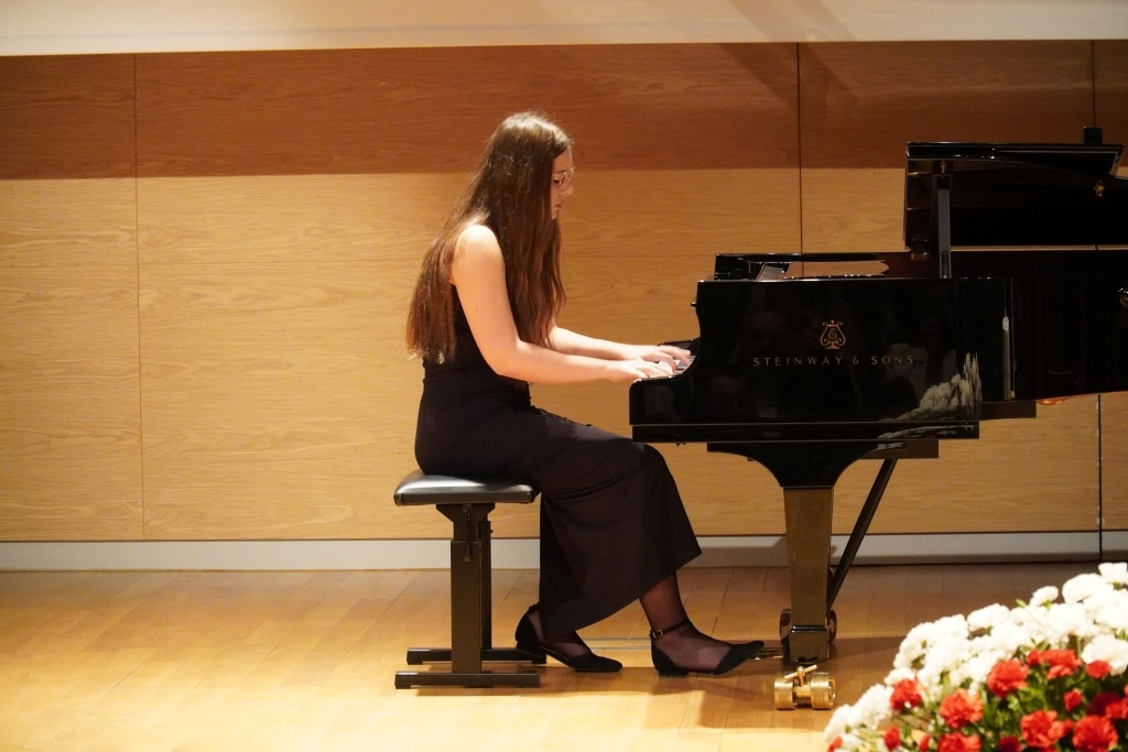 Dziewczyna gra na fortepianie Steinway & Sons podczas występu