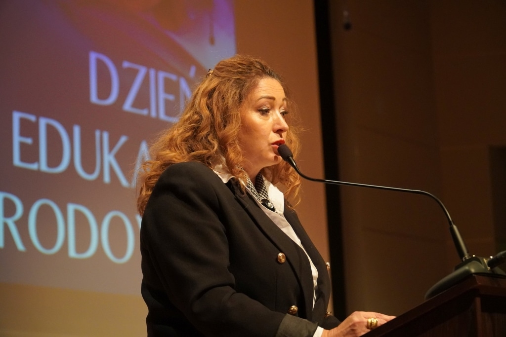 Kobieta przemawia na tle napisu "Dzień Edukacji Narodowej
