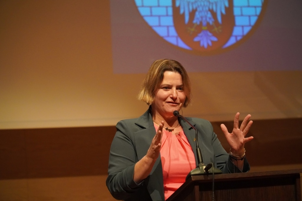 Kobieta przemawia na tle godła podczas Dnia Edukacji Narodowej.