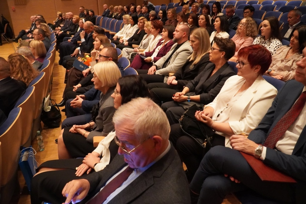 Ludzie siedzą na sali podczas uroczystości Dnia Edukacji Narodowej.