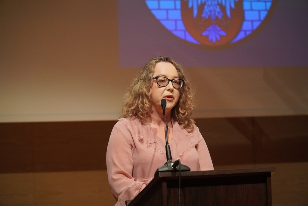 Kobieta w okularach przemawia przy mównicy podczas Dnia Edukacji Narodowej.