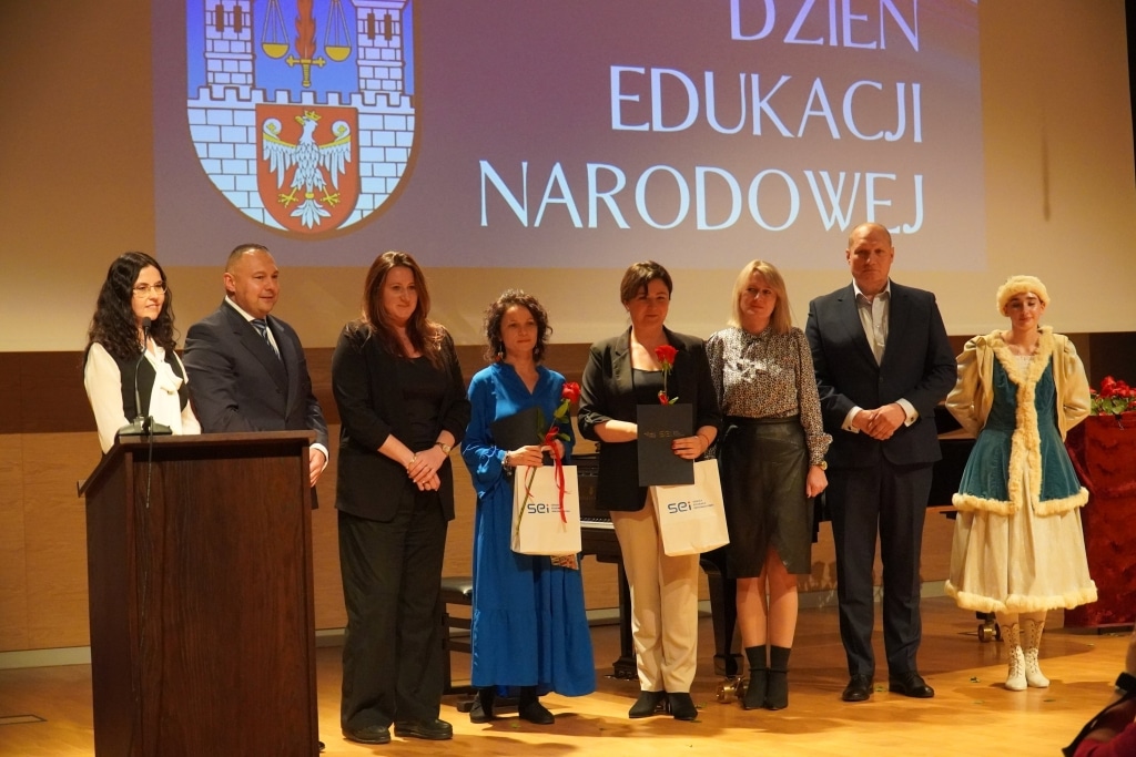 Grupa osób odbiera nagrody na scenie podczas Dnia Edukacji Narodowej