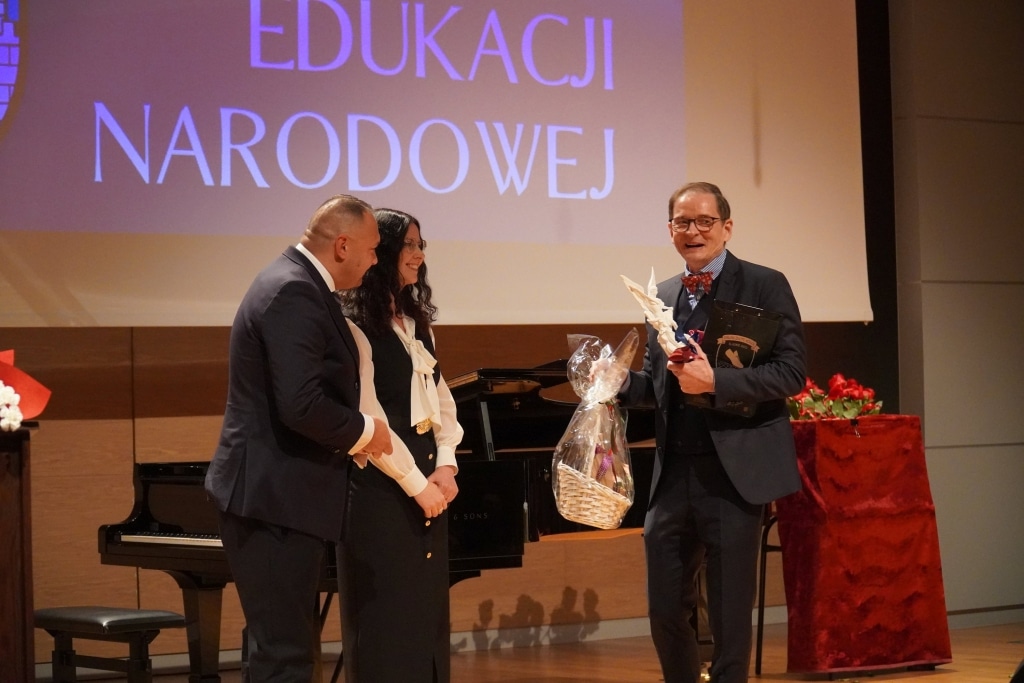 Wręczenie nagród podczas Dnia Edukacji Narodowej, mężczyzna odbiera kosz prezentów.