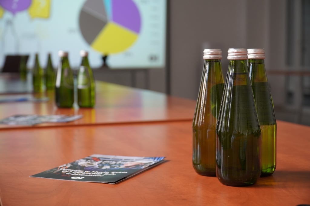 Butelki z wodą na stole podczas wizyty studyjnej w Hucie Szkła O-I w Jarosławiu.