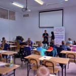 Uczniowie na lekcji w sali z tablicą i projektorem.