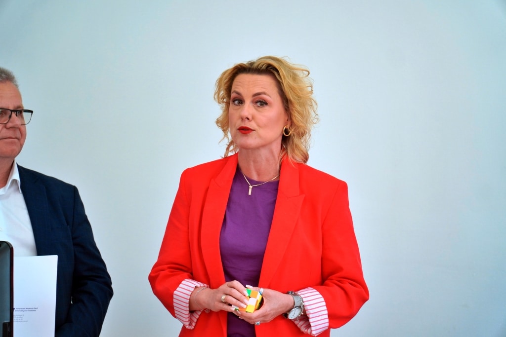 Kobieta w czerwonej marynarce trzyma kostkę na Dniu Jakości Pedagogiki Przedszkolnej