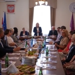 Spotkanie podsumowujące współpracę: kobiety i mężczyźni przy stole w sali konferencyjnej.