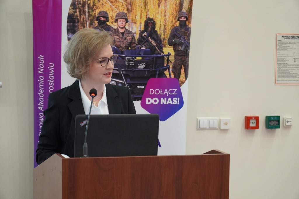 Kobieta przemawia na konferencji naukowej o bezpieczeństwie informacyjnym