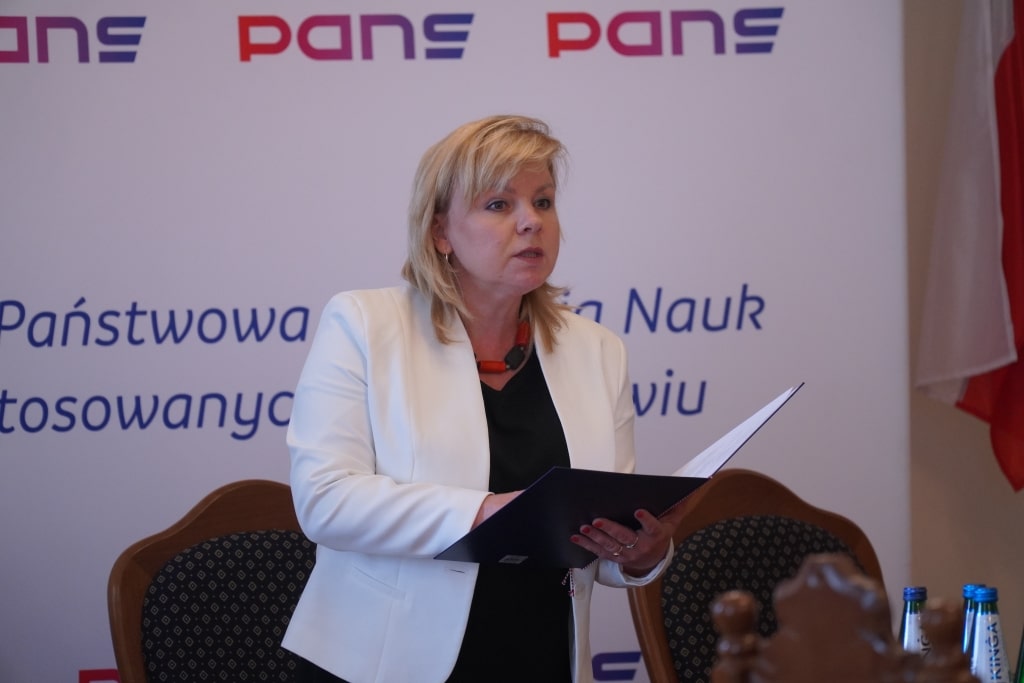 Kobieta w białej marynarce przemawia podczas podpisania porozumień o współpracy