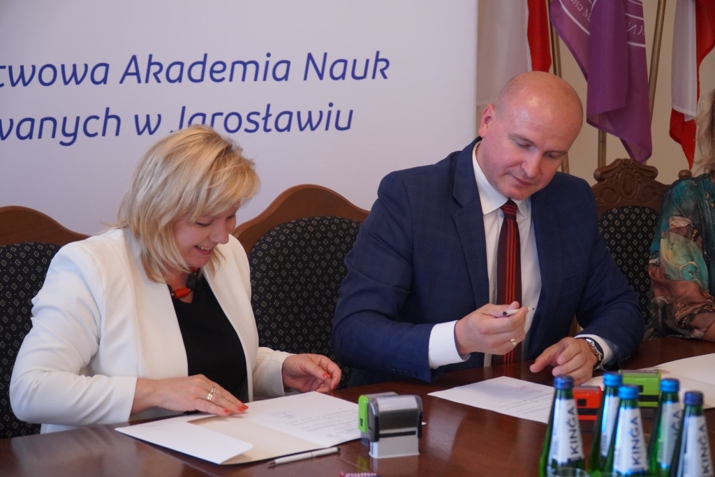 Podpisanie porozumienia o współpracy: Kobieta i mężczyzna przy stole z dokumentami.