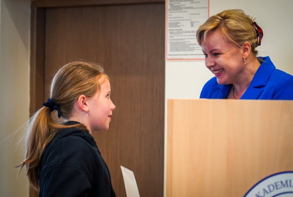 Kobieta w niebieskiej marynarce rozmawia z dziewczynką podczas Festiwalu Kreatywności.