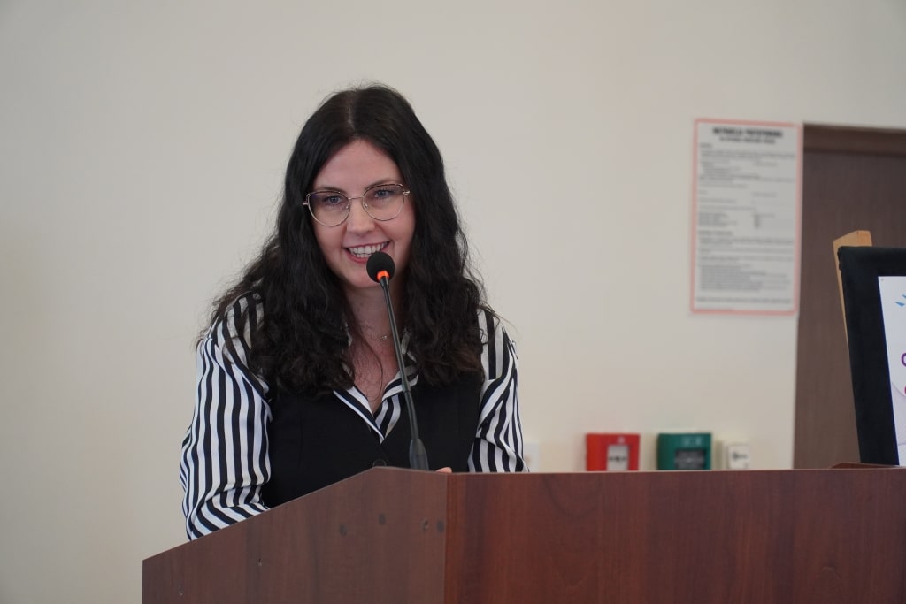 Kobieta w okularach przemawia na konferencji naukowej „Odporność psychiczna”