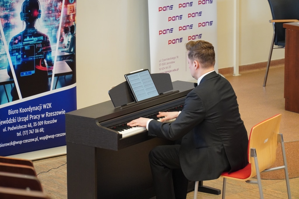 Mężczyzna gra na pianinie cyfrowym podczas konferencji naukowej o odporności psychicznej.