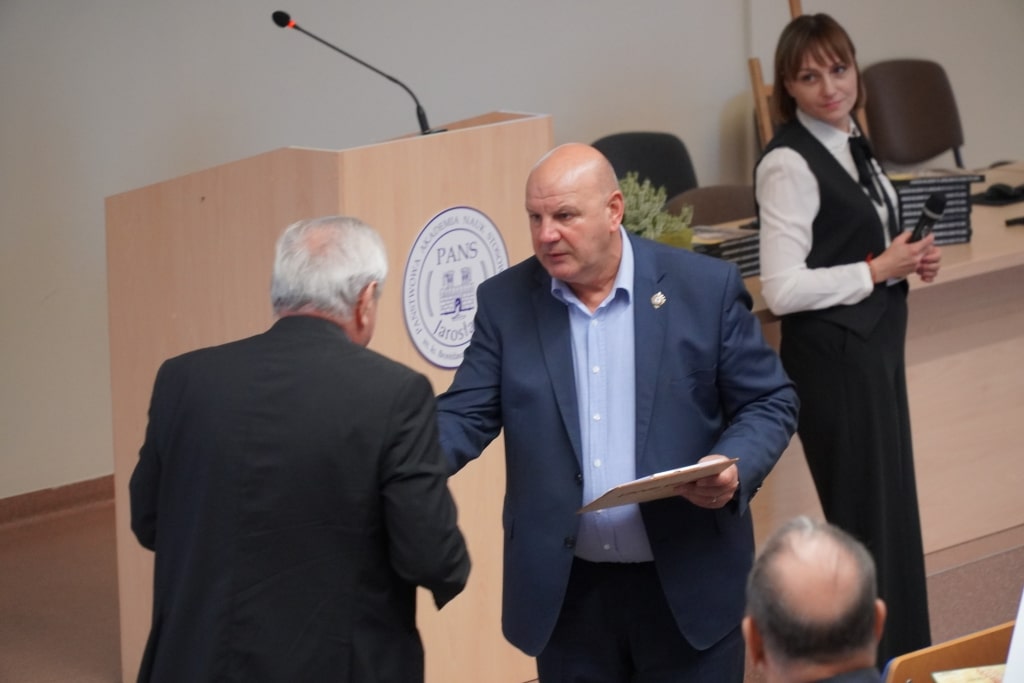 Spotkanie promujące książkę: wręczenie publikacji na tle logo PANS