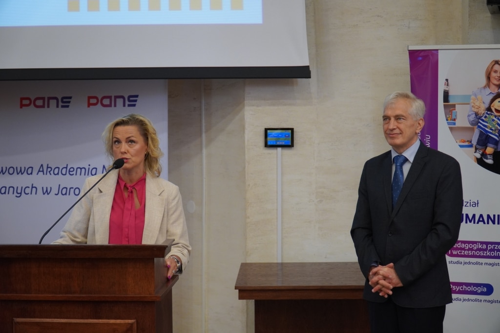 Kobieta przemawia przy mównicy, obok stoi mężczyzna, podczas konferencji w PANS