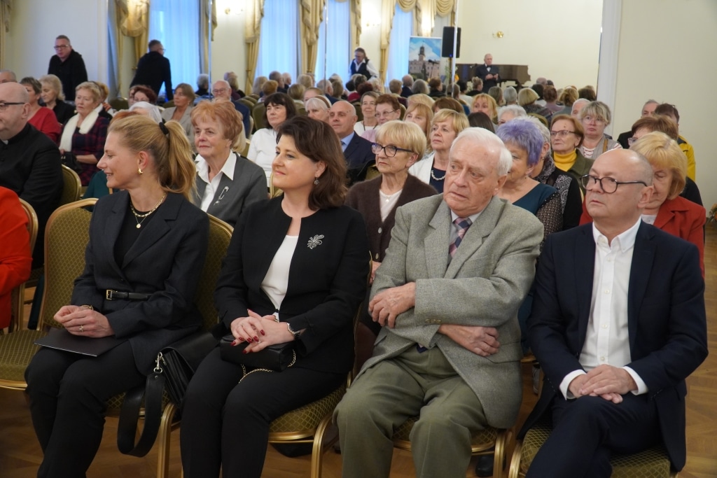 Uczestnicy inauguracji roku akademickiego Akademii Trzeciego Wieku siedzą na sali.