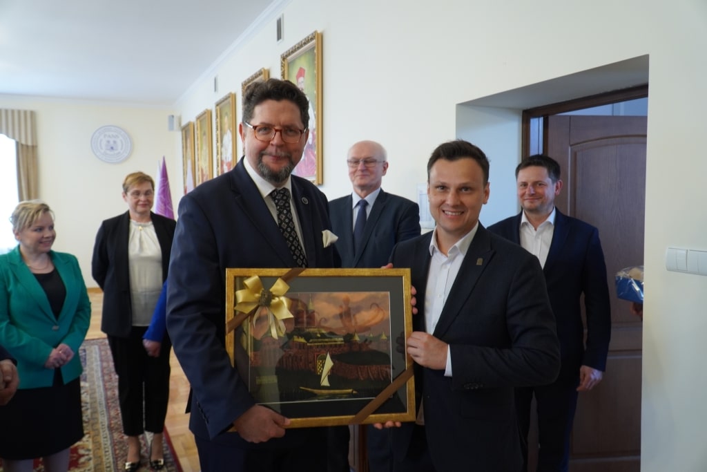 Prof. Andrzej Szeptycki otrzymuje obraz od mężczyzny w garniturze