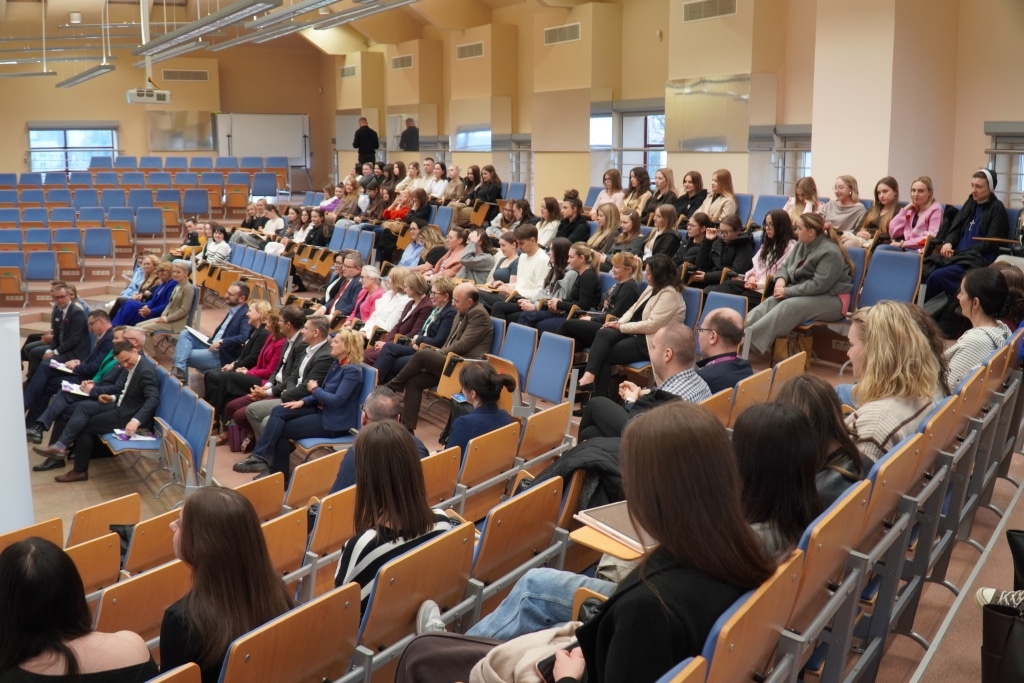 Uczestnicy konferencji naukowej o aktywności fizycznej siedzą na sali wykładowej.