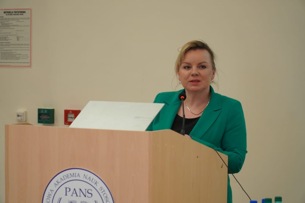 Kobieta w zielonej marynarce przemawia podczas IX Konferencji Naukowej PANS