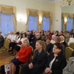 Uczestnicy inauguracji roku akademickiego Akademii Trzeciego Wieku siedzą na sali.