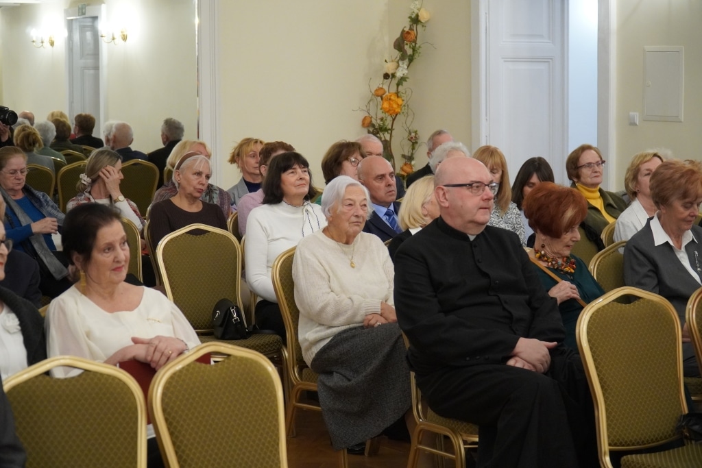 Uczestnicy inauguracji roku akademickiego Akademii Trzeciego Wieku siedzą na sali.